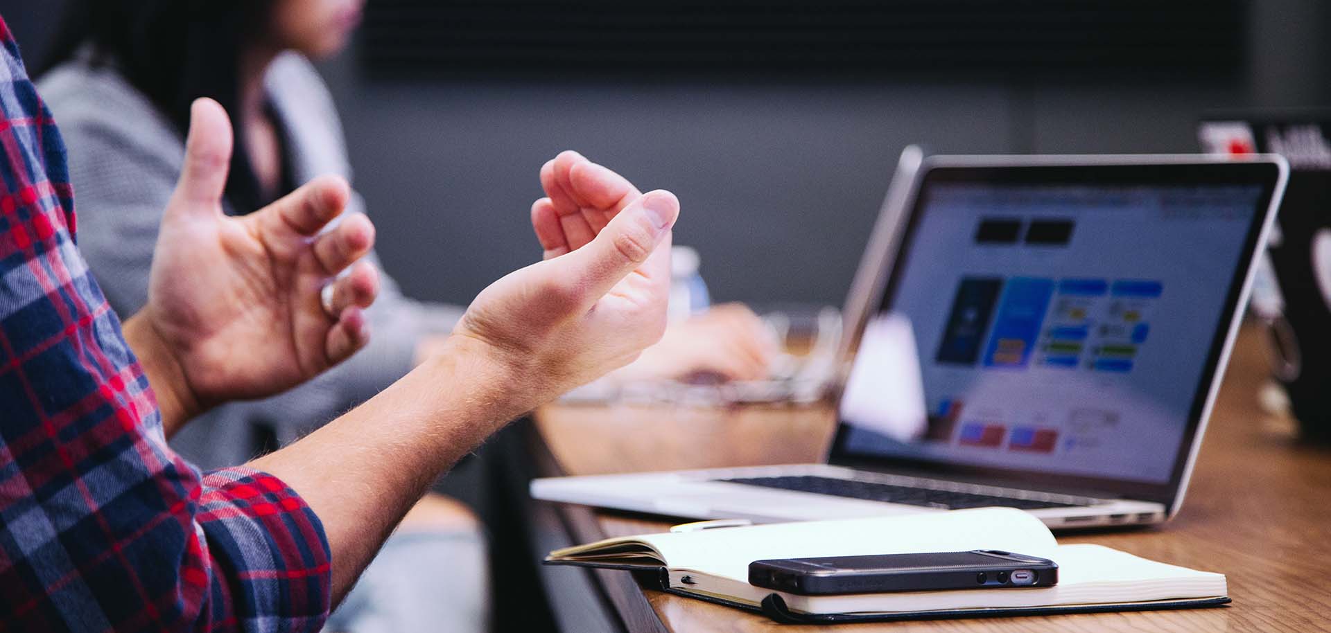 A person gesturing in front of a laptop