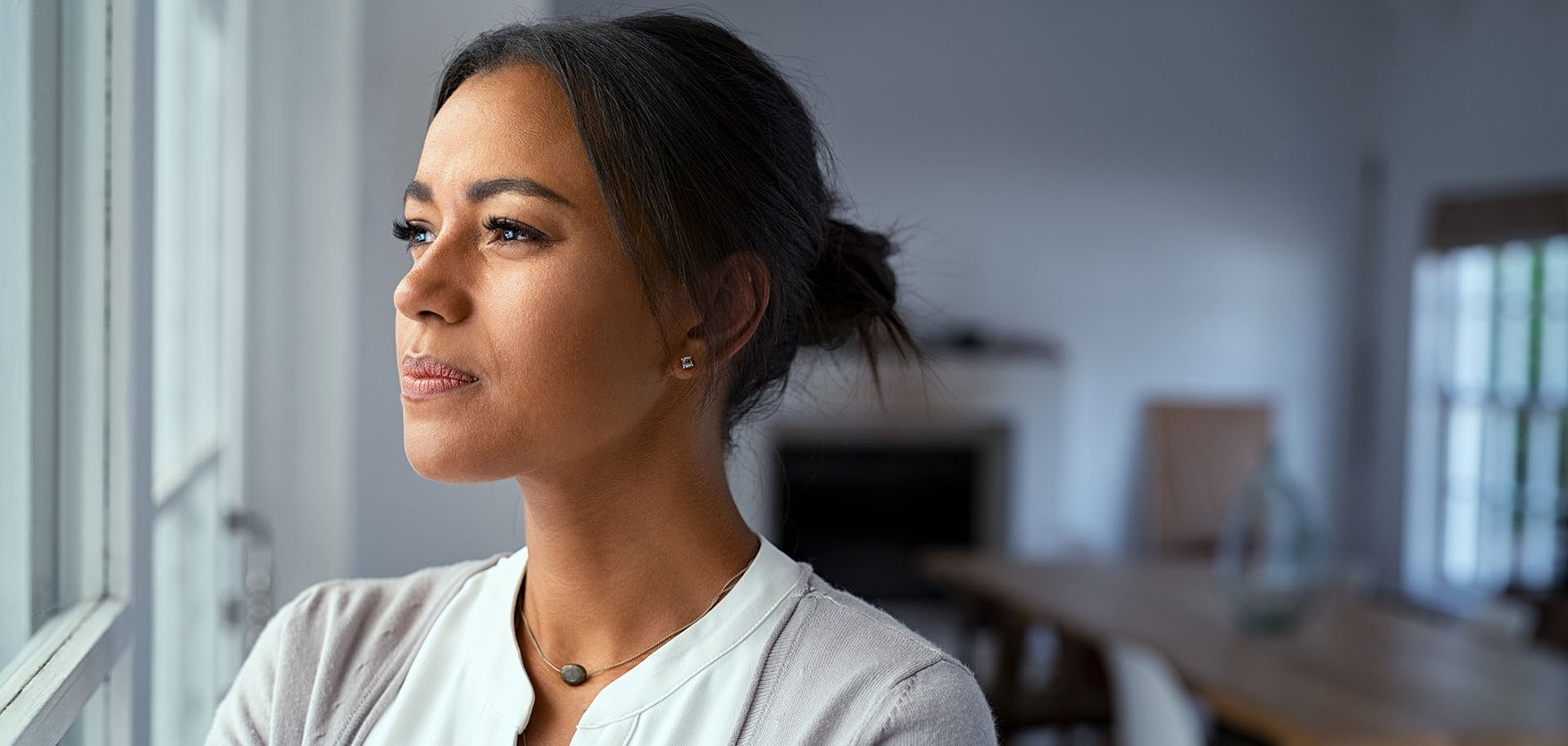A woman with a doubtful expression looking out of a window